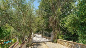 A stone pathway leading to a gated entrance surrounded by lush greenery.