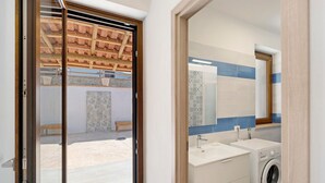 A bathroom with a washing machine, a sink, and a mirror.