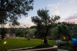 Un giardino curato con un recinto in legno, un albero e un pannello solare su un edificio.
