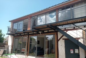 Ein zweigeschossiges Gebäude mit einem Balkon, großen Schiebeg lass Türen und einer Treppe.