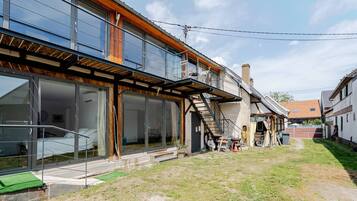 A modern house with a large glass window, a wooden deck, and a staircase leading to the upper floor.