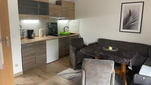 Una cucina compatta con zona pranzo, mobili in legno, una macchina da caffè e un quadro appeso al muro.