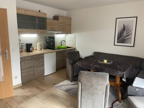 Een compacte keuken met een eethoek, houten kastjes, een koffieapparaat en een lijstwerk aan de muur.