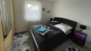 Camera da letto con un letto, un armadio, un comodino, una lampada e una finestra con tende.