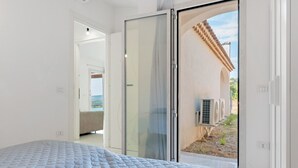 Ein Schlafzimmer mit Bett und einer Schiebetür zu einem Außenbereich mit Klimaanlagen.