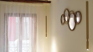 Een kamer met een groot raam, een hangende吊灯 en drie spiegels aan de muur.