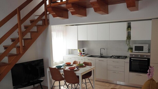 Een moderne keuken met witte kasten, een eettafel met stoelen, een inbouwoven en een magnetron.