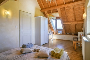 A bedroom with a bed, pillows, a chair, a desk, and a window.
