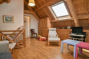 Una stanza in stile loft con soffitto in legno, un lucernario, una televisione, una poltrona, un tavolo e una libreria.