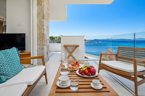 Ein Balkon mit einem Esstisch für das Frühstück, einer Couch und einem Fernseher.