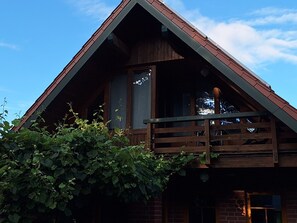 Eine Holzhütte mit Balkon, Fenster und einer Backsteinmauer.
