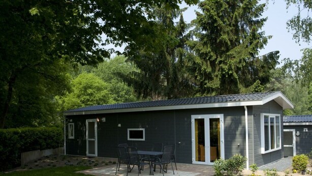 Ein kleines, eingeschossiges Gebäude mit einer Terrasse, einem Tisch und Stühlen.