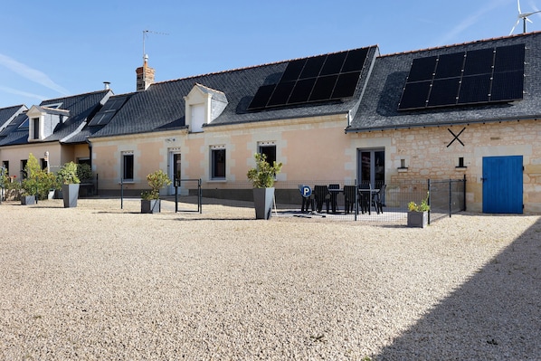 A building with solar panels, a gravel driveway, and a blue door.