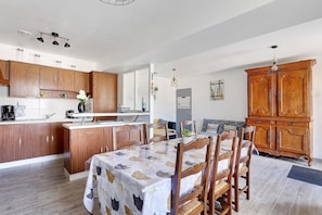 Une cuisine moderne avec des meubles de rangement en bois, une table à manger avec des chaises et un grand meuble en bois.