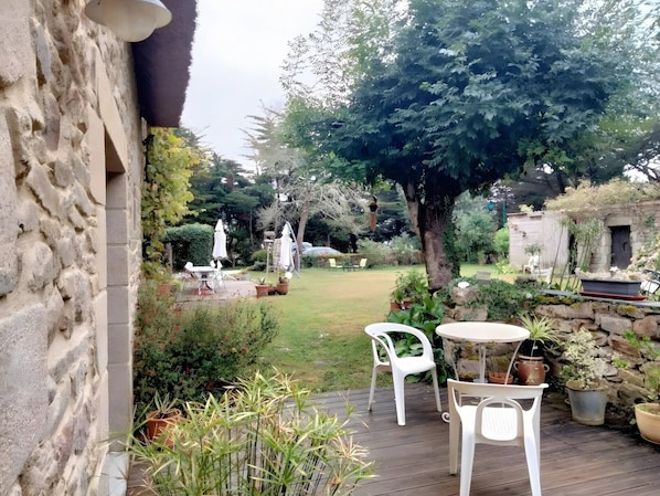Eine Terrasse mit einer Steinsäule, einem Tisch mit Stühlen und Topfpflanzen.