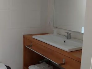 Ein Badezimmer mit einem weißen Waschbecken, einem Spiegel darüber und einer hölzernen Waschtischbank.