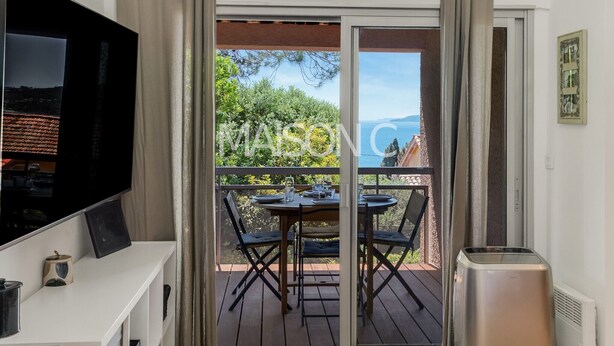 Ein Balkon mit Tisch und Stühlen, einem Fernseher und einem Mülleimer.