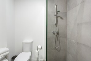 Ein Badezimmer mit Toilette, Dusche und einer Rolle Toilettenpapier.