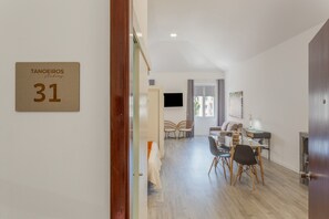 Ein modernes Interieur mit Essbereich, einer Couch und einem an der Wand befestigten Fernseher.