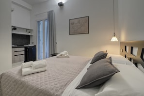 Een hotelkamer met een bed, een bureau, een stoel, een raam met gordijnen en een wanddecoratie.