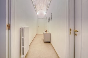 Een gang met een radiator, een kast en een deur met een gouden handgreep.