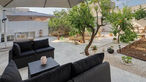 An outdoor seating area with a large umbrella, black sofas, and a small table with a vase.