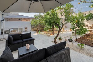 An outdoor seating area with a large umbrella, black sofas, and a small table with a vase.