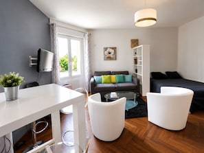 A modern living room with a sofa, a coffee table, a TV, and a bookshelf. - Elegant | Studio | Downtown Nantes (Nantes)