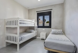 Ein Schlafzimmer mit Etagenbetten, einem Einzelbett, einem kleinen Nachttisch und einem Fenster mit Blick.