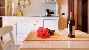 A kitchen with a dining table, a bottle of wine, a glass, and a red hibiscus flower.