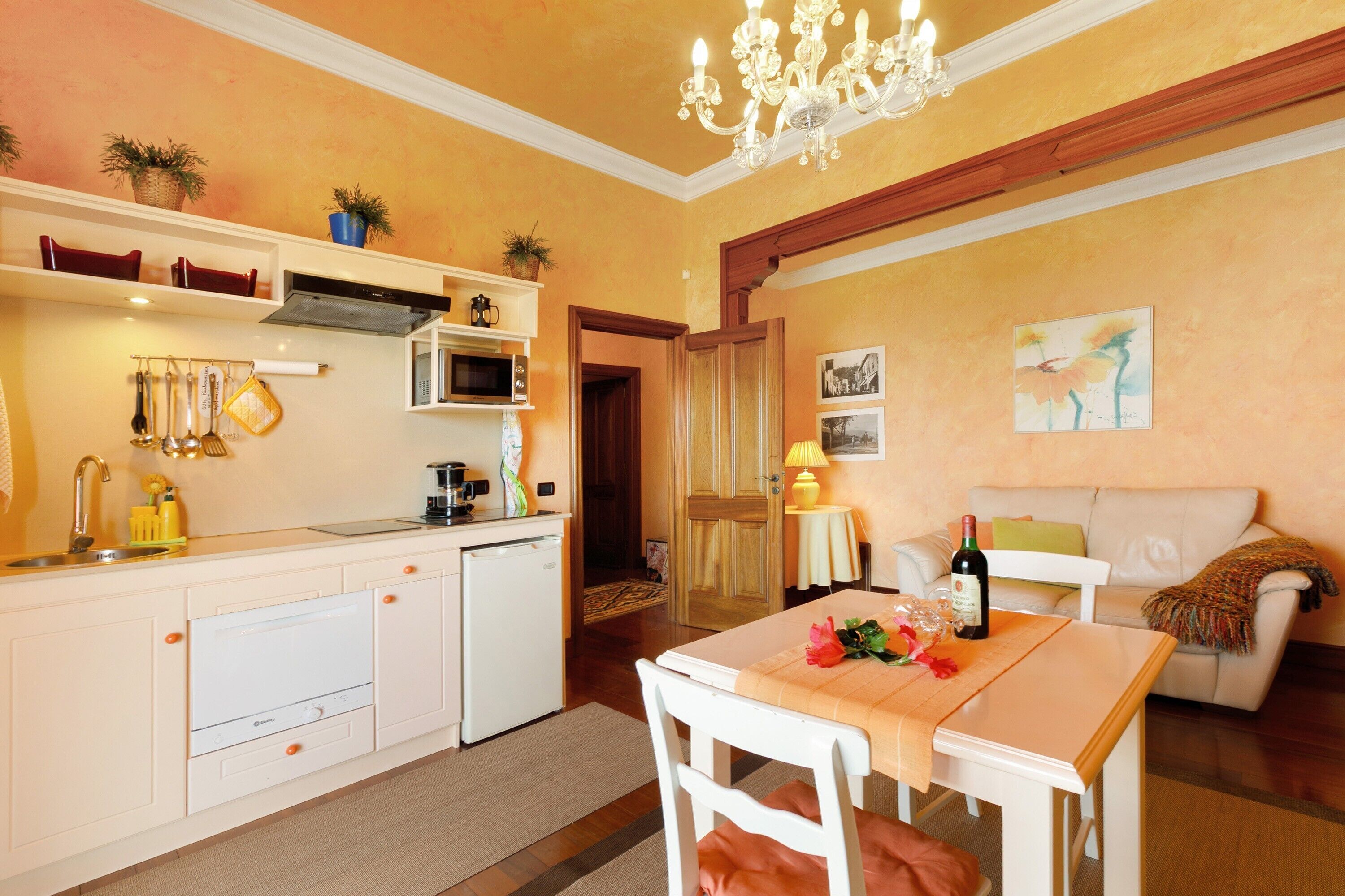 Een kleine woonruimte met een kitchenette, eethoek en een bank.