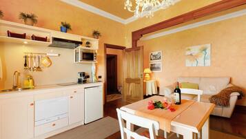 Een kleine woonruimte met een kitchenette, eethoek en een bank.