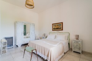 Ein Schlafzimmer mit einem Bett, einem Schminktisch, einem Stuhl, einer Lampe und einem Bild an der Wand.