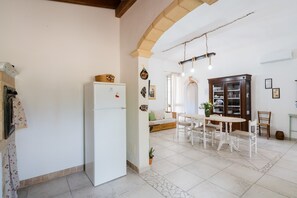 Eine Küche mit Kühlschrank, Esstisch, Stühlen und einem Holzschrank.