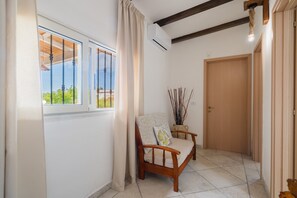 Ein Korridor mit einer hölzernen Bank, einer Tür und einem Fenster mit Vorhängen.