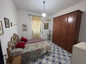Una camera da letto con un letto, un armadio, una ventola a soffitto e una finestra con tende.
