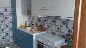 Une cuisine compacte équipée d’une cuisinière, d’un four et d’un petit plan de travail sur lequel sont disposés divers objets.