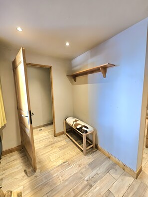 Ein Zimmer mit einer Holzbänke, einem Holzbodenregal und einer Tür zu einem anderen Raum.