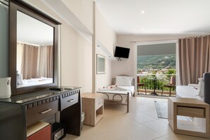 Une chambre d’hôtel avec un balcon, un lit, une télévision, un bureau et une salle de bain.