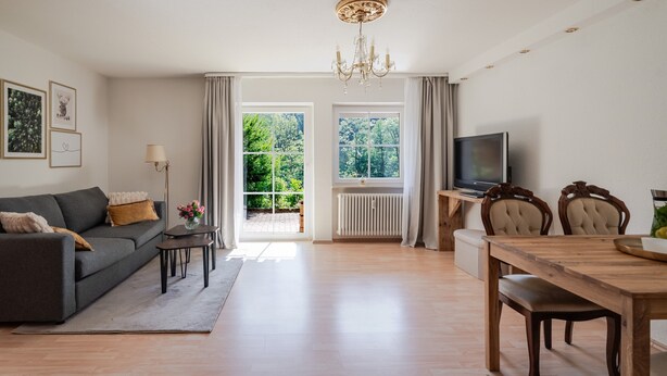A modern living room with a sofa, TV, dining table, and chairs. - Apartment 'Rai Mattiss' with Mountain View, Private Terrace and Wi-Fi (Oberharmersbach)