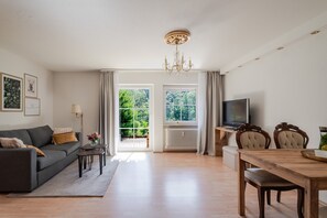 Een moderne woonkamer met een bank, televisie, eettafel en stoelen.