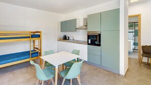 A bunk bed, a kitchen with a stove, and a dining area with chairs. - Apartment 3 - Leucosia with Sea View, Private Terrace, and Air Conditioning (Casal Velino)