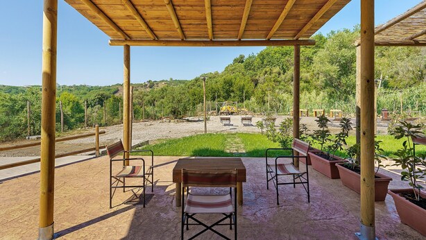 A wooden pergola with a table and chairs, surrounded by potted plants and a view of a green landscape. - Apartment 3 - Leucosia with Sea View, Private Terrace, and Air Conditioning (Casal Velino)