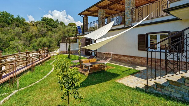 A house with a patio, outdoor furniture, and a wooden deck. - Calipso Apartment with Private Garden and Air Conditioning (Casal Velino)