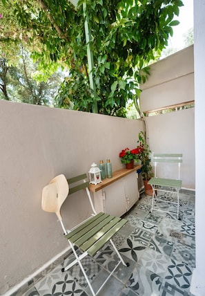 A patio area with a bench, a small table, and potted plants. - Boukamvillia Apartment Just 500m From Nidri Beach (Lefkada)