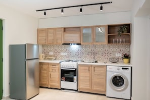 A compact kitchen with a refrigerator, stove, oven, and washing machine. - Boukamvillia Apartment Just 500m From Nidri Beach (Lefkada)