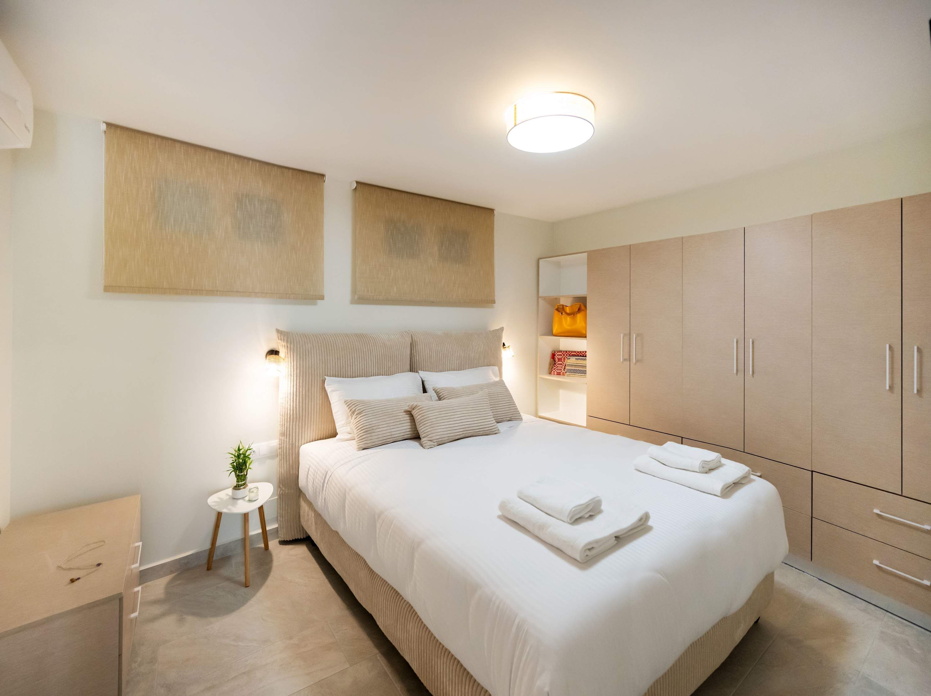 Une chambre moderne avec un grand lit, des tables de chevet, une armoire et des œuvres d’art accrochées au mur.