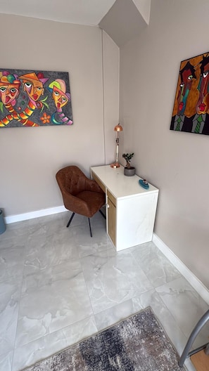 A modern room with a white desk, a brown chair, and two abstract paintings on the walls. - Spacious Modern Home in Whitefield (Bury)