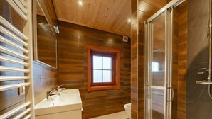 Ein modernes Badezimmer mit Holzwand, Fenster, Dusche und Waschbecken.