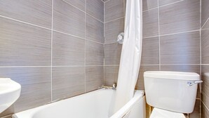 Et badeværelse med badekar, toilet og håndvask.